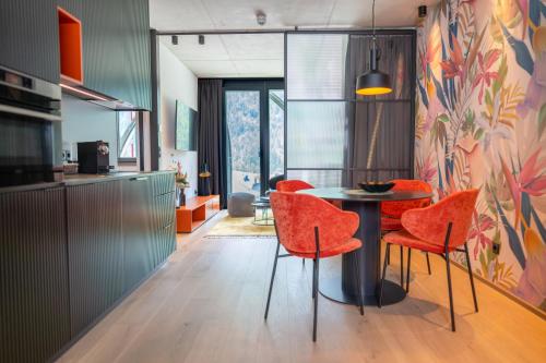 a kitchen with a table and orange chairs at Lifesteil Aparthotel in Umhausen