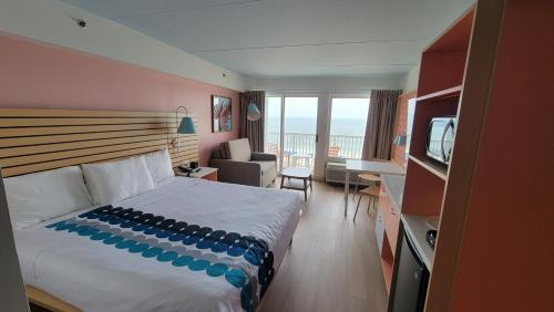 a bedroom with a bed and a living room with a television at Golden Sands Oceanfront Hotel in Carolina Beach