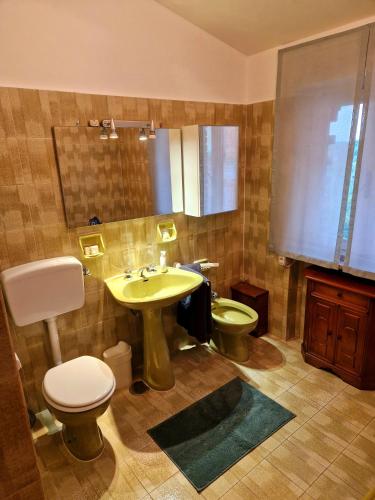 ein Badezimmer mit einem gelben Waschbecken und einem WC in der Unterkunft Casa nostra in Cisterna dʼAsti