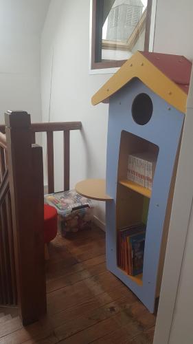 ein Kinderspielhaus mit einem Tisch und einem Bücherregal in der Unterkunft Au rayon de soleil in Trédias