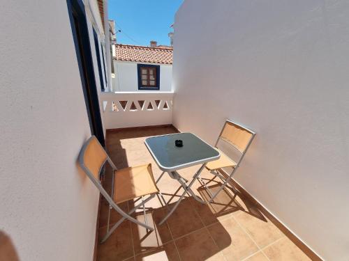 een kleine tafel en stoelen op een klein balkon bij Só Mar in Vila Nova de Milfontes