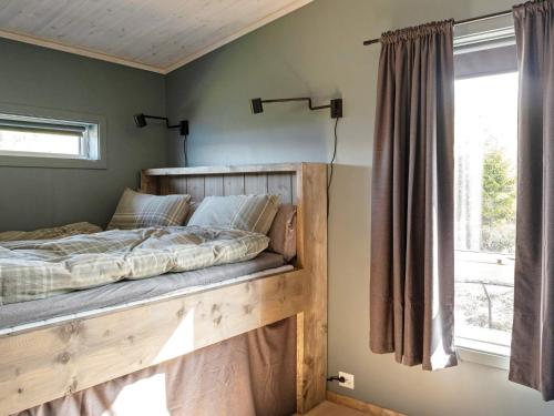 1 dormitorio con cama de madera y ventana en Holiday home INDERØY, 