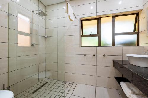 a bathroom with a glass shower and a sink at African Sky Hotels - Pine Lake Inn in White River