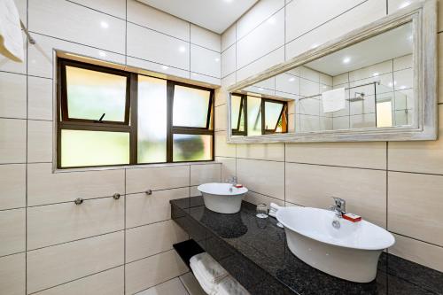 a bathroom with two sinks and a mirror at African Sky Hotels - Pine Lake Inn in White River