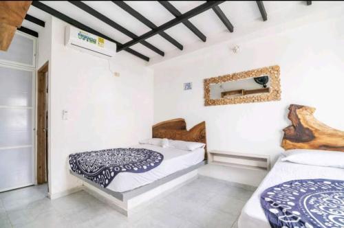 two beds in a room with white walls at AGUAMARINA House in San Bernardo del Viento