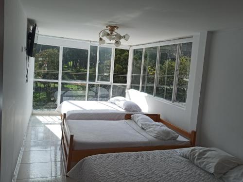 twee bedden in een kamer met een raam bij Hotel Mi Gloria in Tunja