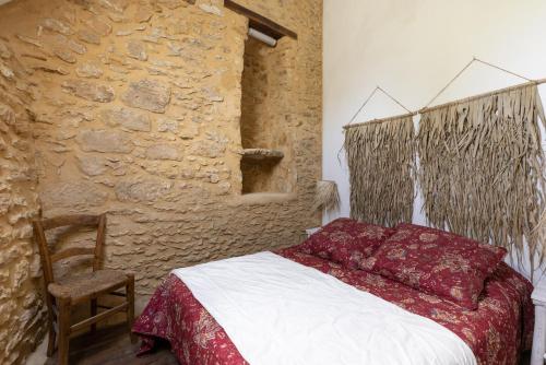 a bedroom with a bed and a stone wall at Domaine Les Maurelles in Milhac