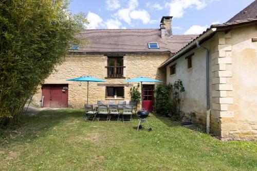 a backyard with a grill and chairs and umbrellas at Domaine Les Maurelles in Milhac