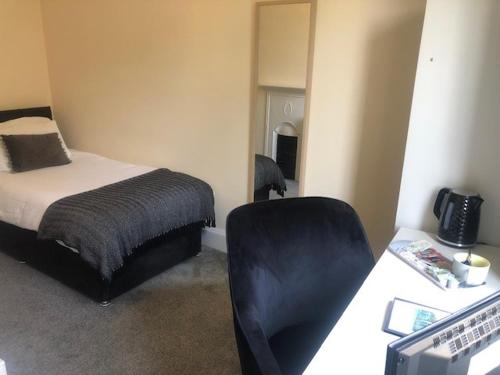 a bedroom with a bed and a desk with a chair at Mirfield Monastery B&B in Mirfield