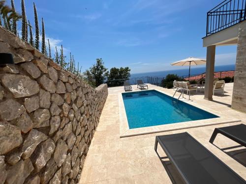 a swimming pool next to a stone wall at Family Vacation Villa Rezevici in Budva