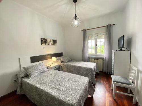 a bedroom with two beds and a tv and a chair at Casa Elsa in Torrelavega