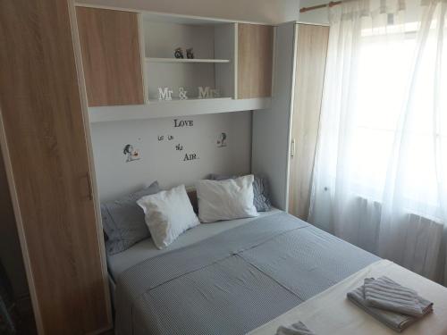 a small bedroom with a bed and a window at Apartment San in Ližnjan