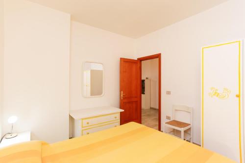 a white bedroom with a bed and a mirror at Bilo Mare 2 in Budoni