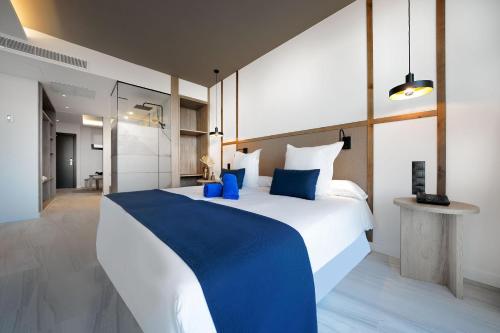 um quarto com uma grande cama branca com almofadas azuis em H10 Costa Mogán em Playa del Cura