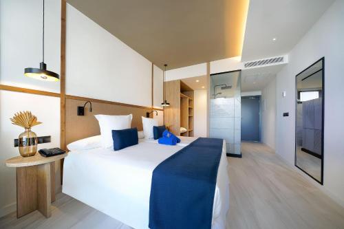 a bedroom with a large white bed with a blue blanket at H10 Costa Mogán in Playa del Cura