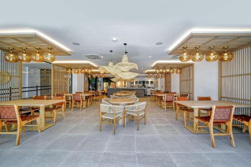 a dining room with tables and chairs and chandeliers at H10 Costa Mogán - Adults Only in Playa del Cura