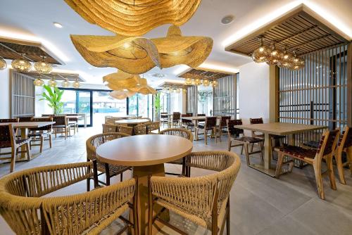 a restaurant with tables and chairs and a chandelier at H10 Costa Mogán - Adults Only in Playa del Cura