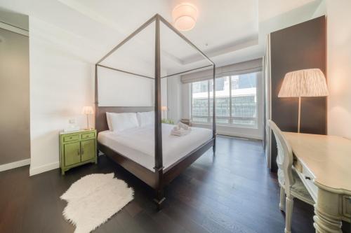 a bedroom with a four poster bed and a desk at Limestone House, Dubai International Financial Centre - Mint Stay in Dubai
