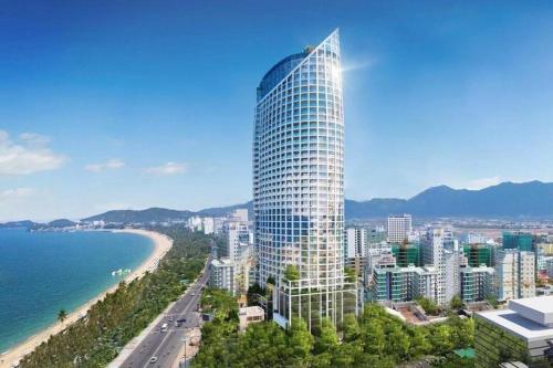 a tall building next to a beach and the ocean at Moonlight Bay Panorama Condotel Ocean View in Nha Trang