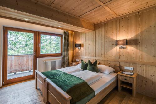 - une chambre avec un grand lit dans une pièce dotée de murs en bois dans l'établissement Ciasa Agreiter, à La Villa