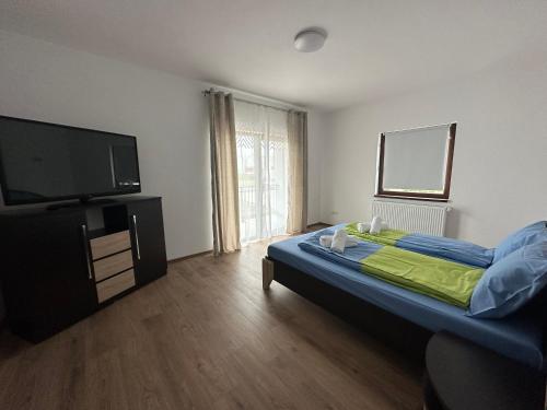 a bedroom with a bed and a flat screen tv at Dacia Apartments in Sebeş