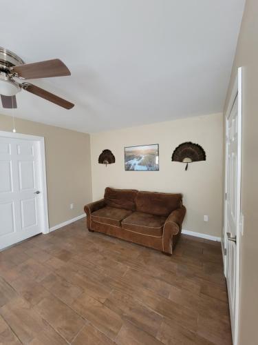 a living room with a brown couch and a ceiling fan at Katahdin's Shadow Lodge in Linneus