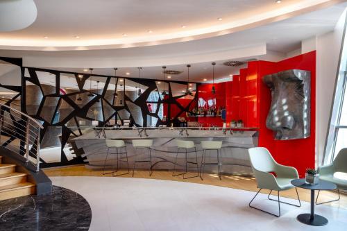 a restaurant with a bar with red walls and chairs at UNA Hotels Malpensa in Cerro Maggiore