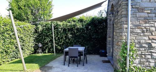 a patio with a table and chairs under an umbrella at B&B Domaine du Vieux Chêne in Stoumont
