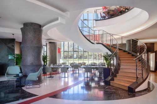 a spiral staircase in a building with tables and chairs at UNA Hotels Malpensa in Cerro Maggiore