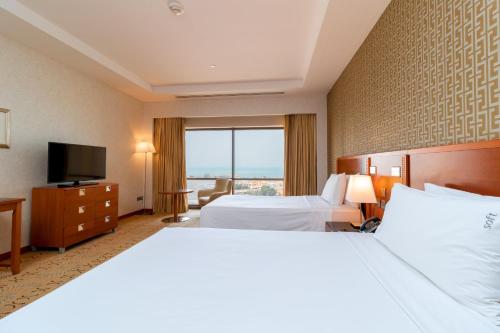 a hotel room with two beds and a television at Holiday Inn Kuwait by IHG in Kuwait