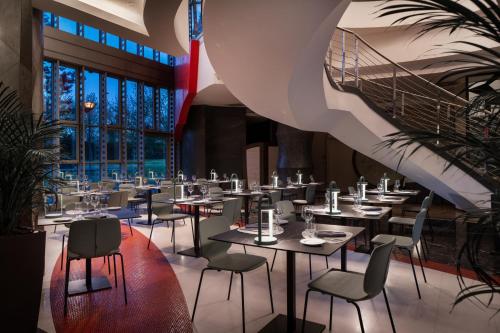 a restaurant with tables and chairs and a spiral staircase at UNAHOTELS Malpensa in Cerro Maggiore
