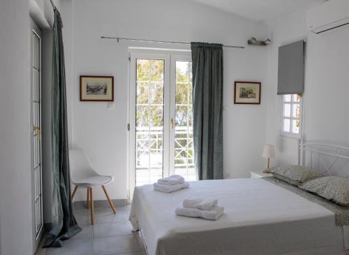 a white bedroom with a bed and a window at Green Villa Aegina in Aegenitissa