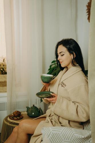 a woman sitting in a towel holding a bowl at Hotel & Spa DENINNA in Vinnytsya