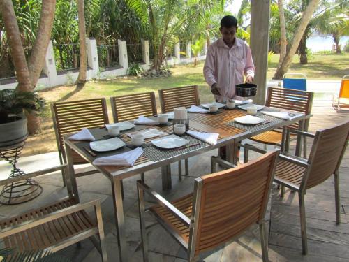 a man standing next to a wooden table with chairs at Isana Beach House in Tangalle