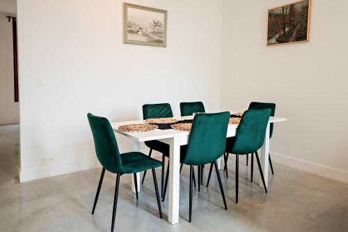 a white table with green chairs in a room at Luxury Suites South by Rikas Hotels in Antwerp