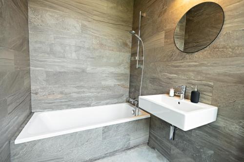 a bathroom with a sink and a bath tub and a mirror at Luxury Suites South by Rikas Hotels in Antwerp