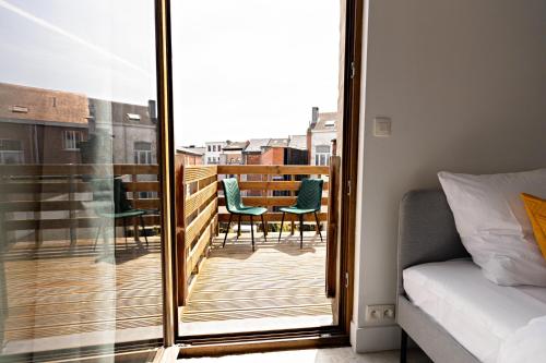 a bedroom with a balcony with a bed and chairs at Luxury Suite South in Antwerp