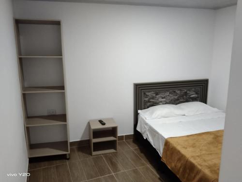 een slaapkamer met een bed en een boekenplank bij Hotel Brisas Del Rio SH in Tuluá