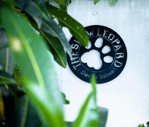 un panneau noir sur un mur avec un sanctuaire de pattes de chien dans l'établissement The Slow Leopard, à Dar es Salaam