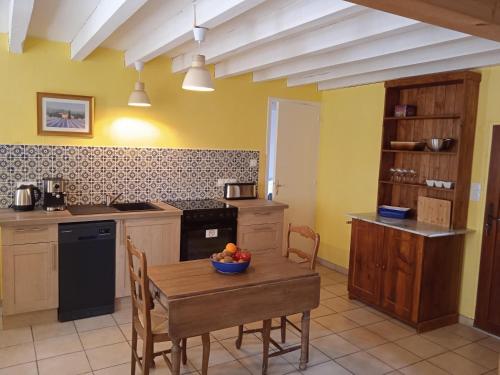 una cocina con una mesa con un bol de fruta. en Charming detached 2 bedroom ancient house in medieval quarter of a small town in the Pays de la Loire, France, en Sillé-le-Guillaume