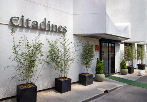 un bâtiment avec des plantes en pot devant lui dans l'établissement Citadines La Défense Paris, à Courbevoie