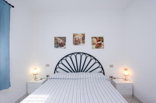 a white bedroom with a bed and two lamps at La Ena Casa Vacanze in Budoni