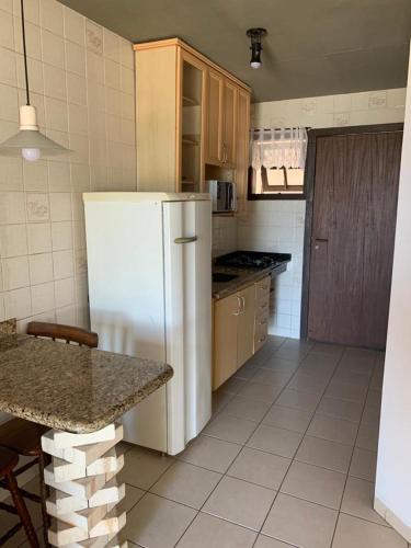 a kitchen with a white refrigerator and a table at Pousada Bangalôs Da Mole - Florianópolis in Florianópolis