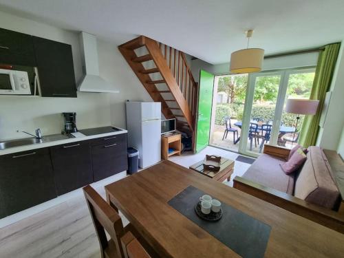 Il comprend une cuisine et un salon avec une table à manger. dans l'établissement La Cabane Apolonia maison 6 pp Piscine en bord lac, à Aureilhan