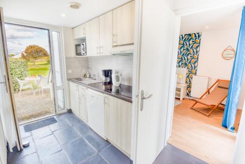 une cuisine avec des armoires blanches et une porte donnant sur un patio dans l'établissement Grand duplex bord de plage avec Terrasse par Groom, à Guidel