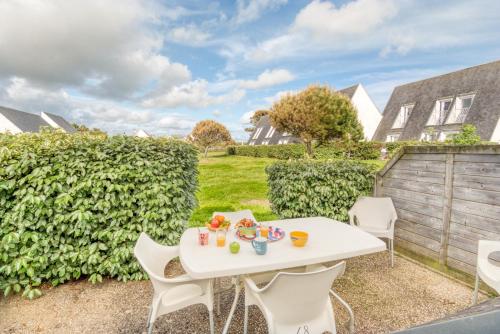 - une table et des chaises blanches dans l'arrière-cour d'une maison dans l'établissement Grand duplex bord de plage avec Terrasse par Groom, à Guidel