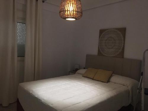 ein Schlafzimmer mit einem weißen Bett und einem Kronleuchter in der Unterkunft San Jacinto 69 Triana in Sevilla