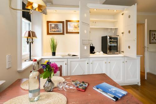a kitchen with white cabinets and a table with flowers at Hotel Parkresidenz Christian VIII in Archsum