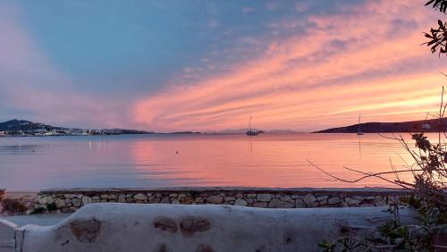 a sunset over a body of water with a boat at Ricardo by the sea in Parikia
