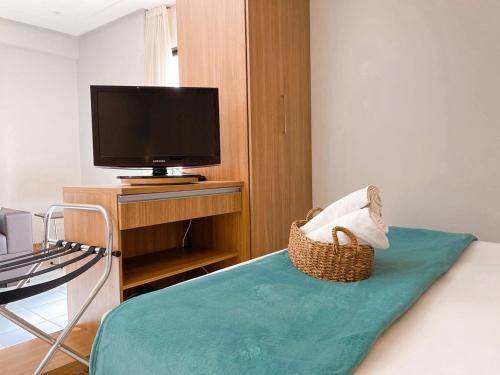 a room with a bed with a television and a chair at STAY Sun Square in Goiânia